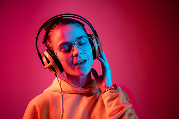 Image showing Fashion pretty woman with headphones listening to music over neon background