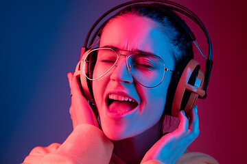 Image showing Fashion pretty woman with headphones listening to music over neon background