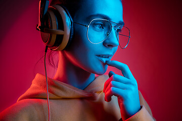 Image showing Fashion pretty woman with headphones listening to music over neon background