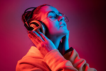 Image showing Fashion pretty woman with headphones listening to music over neon background