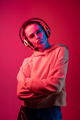 Image showing Fashion pretty woman with headphones listening to music over neon background