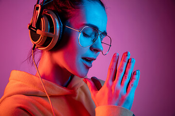 Image showing Fashion pretty woman with headphones listening to music over neon background