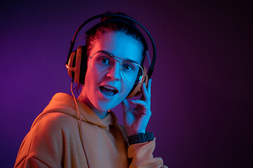 Image showing Fashion pretty woman with headphones listening to music over neon background