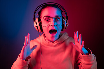 Image showing Fashion pretty woman with headphones listening to music over neon background