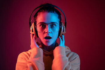 Image showing Fashion pretty woman with headphones listening to music over neon background