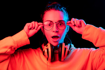 Image showing Fashion pretty woman with headphones listening to music over neon background