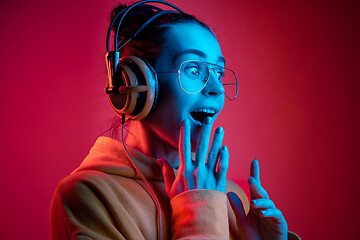 Image showing Fashion pretty woman with headphones listening to music over neon background