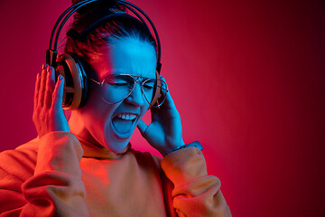 Image showing Fashion pretty woman with headphones listening to music over neon background