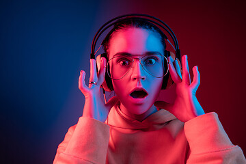 Image showing Fashion pretty woman with headphones listening to music over neon background