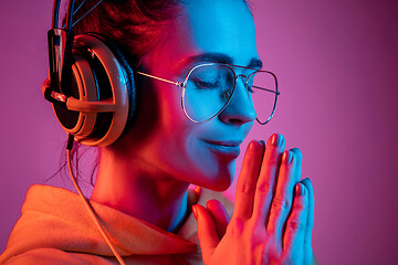 Image showing Fashion pretty woman with headphones listening to music over neon background