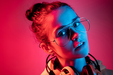 Image showing Fashion pretty woman with headphones listening to music over neon background