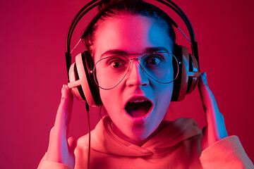 Image showing Fashion pretty woman with headphones listening to music over neon background