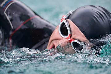 Image showing triathlon athlete swimming on lake wearing wetsuit