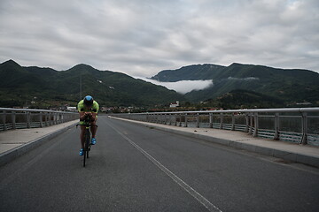 Image showing triathlon athlete riding a bike on morning training