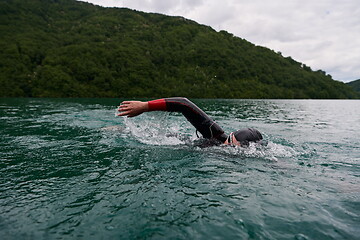 Image showing triathlon athlete swimming on lake wearing wetsuit