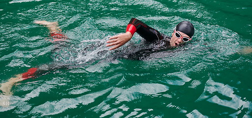 Image showing triathlon athlete swimming on lake wearing wetsuit