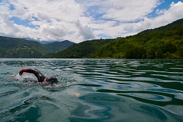 Image showing triathlon athlete swimming on lake wearing wetsuit