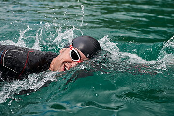 Image showing triathlon athlete swimming on lake wearing wetsuit