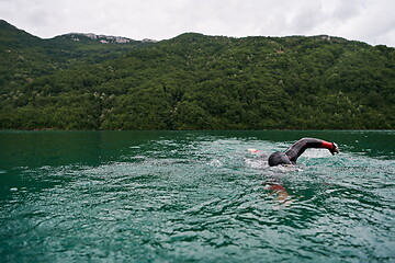 Image showing triathlon athlete swimming on lake wearing wetsuit