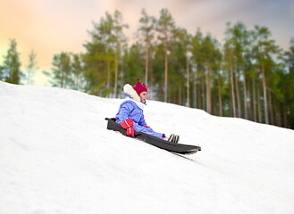 Image showing happy little girl sliding down on sled in winter