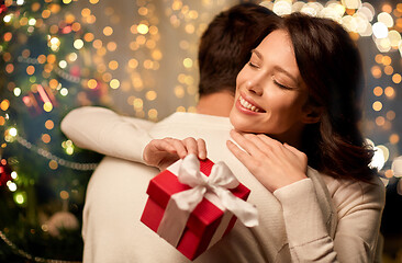 Image showing happy couple with christmas gift hugging at home