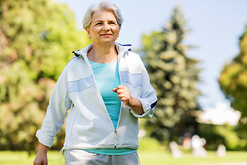 Image showing senior woman running along summer park