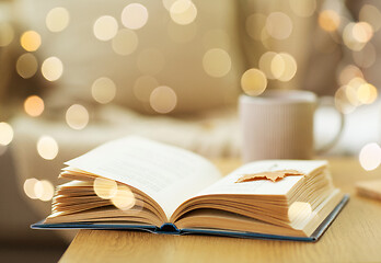 Image showing book with autumn leaf on wooden table at home