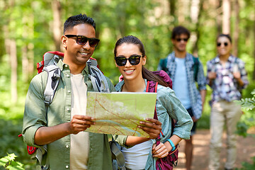 Image showing friends with map and backpacks hiking in forest