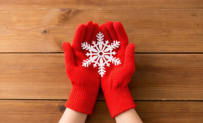 Image showing hands in red woollen gloves holding big snowflake