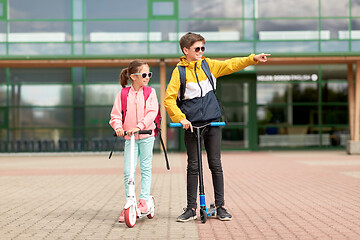 Image showing happy school children with backpacks and scooters