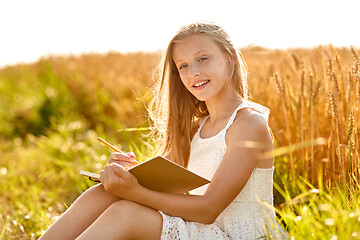 Image showing smiling girl writing to diary on cereal field