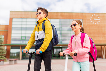 Image showing school children with backpacks riding scooters