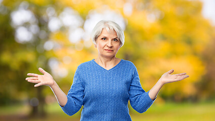 Image showing senior woman shrugging in autumn park