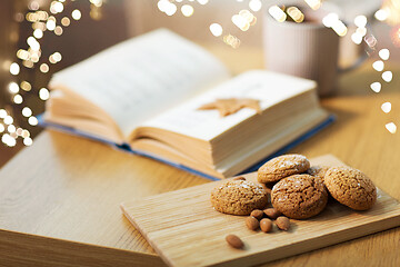 Image showing oat cookies, almonds and book on table at home