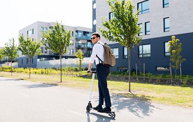 Image showing businessman with backpack riding electric scooter