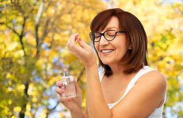 Image showing senior woman smelling perfume from her wrist