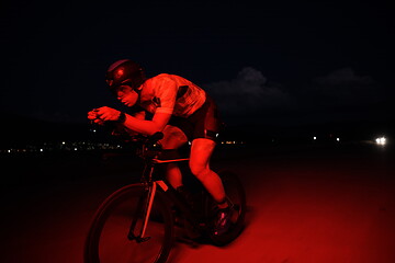 Image showing triathlon athlete riding bike fast at night