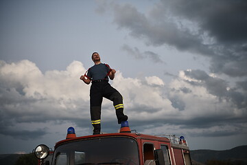 Image showing firefighter out of duty on top of truck