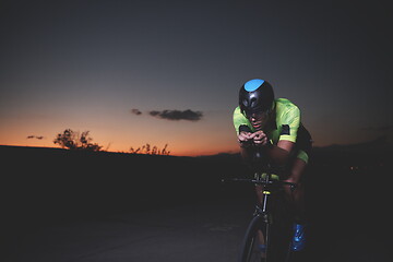 Image showing triathlon athlete riding bike fast at night