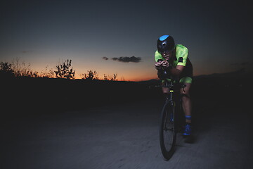 Image showing triathlon athlete riding bike fast at night