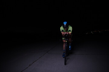 Image showing triathlon athlete riding bike fast at night