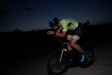 Image showing triathlon athlete riding bike fast at night