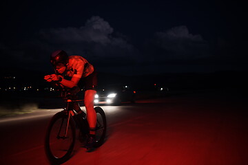 Image showing triathlon athlete riding bike fast at night