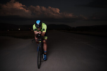 Image showing triathlon athlete riding bike fast at night