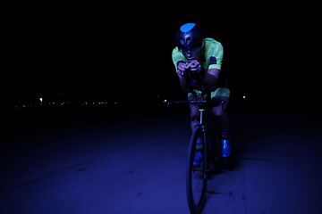 Image showing triathlon athlete riding bike fast at night