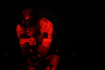 Image showing triathlon athlete riding bike fast at night