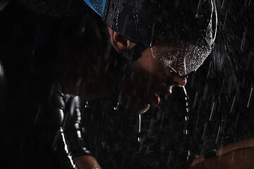 Image showing triathlon athlete riding bike fast on rainy night