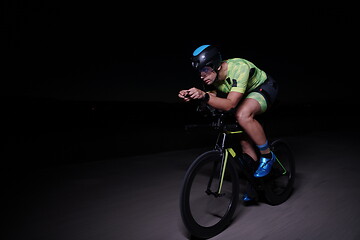 Image showing triathlon athlete riding bike fast at night