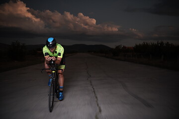 Image showing triathlon athlete riding bike fast at night