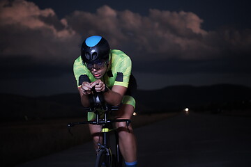 Image showing triathlon athlete riding bike fast at night